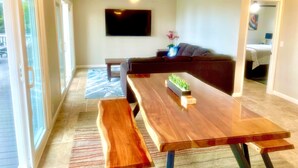 A modern living room with a wooden dining table, bench, and a ceiling fan. - Private Peaceful Beautiful House  (Kailua-Kona)