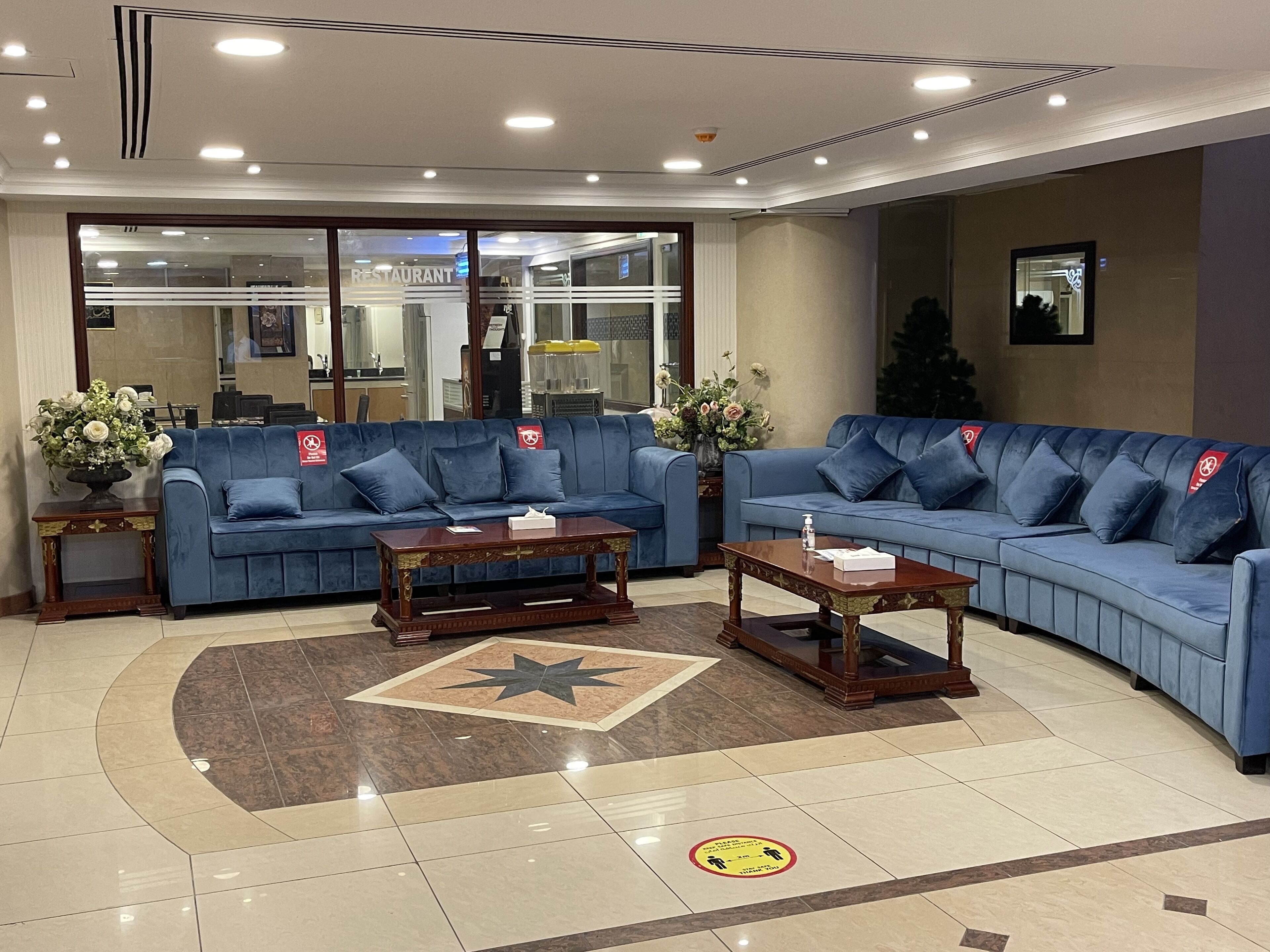 A lobby with two blue sofas, a wooden coffee table, and a decorative rug.