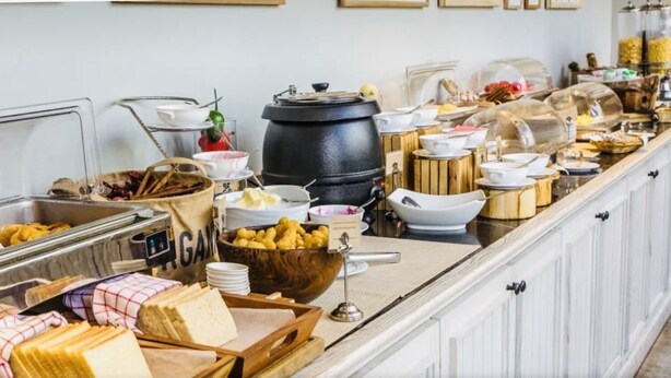 A buffet setup with various food items and containers, including a large black pot, bowls, and baskets. - MOUNT SINA HOTEL BY AURA (Dubai)