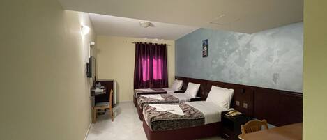 A hotel room with a bed, a desk, a chair, and a small table.