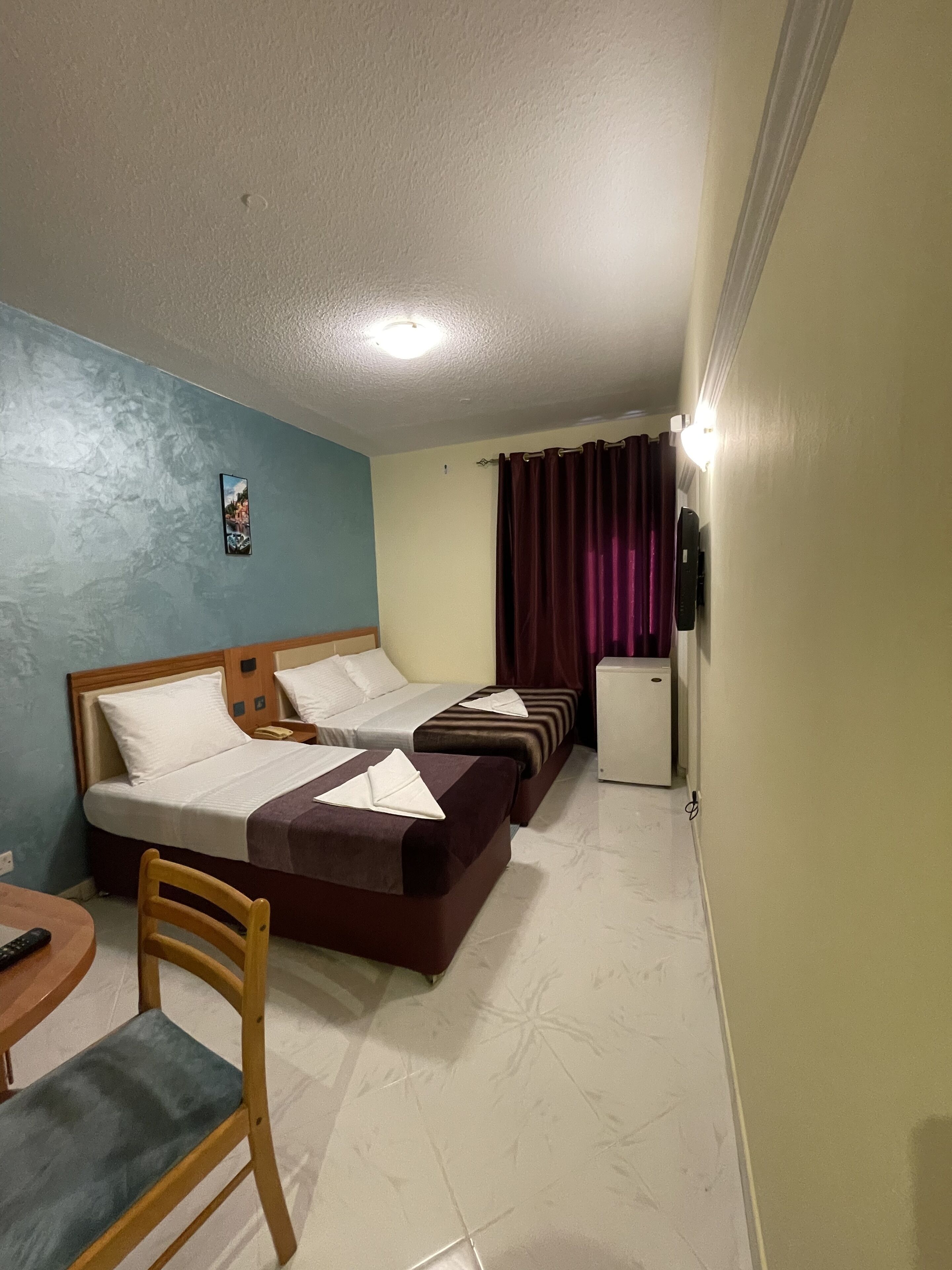 Habitación de hotel con dos camas, un escritorio, una silla y un refrigerador.