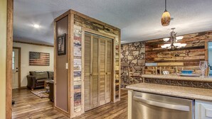 Cucina con mobili in legno, lavastoviglie e parete a parete rivestita in pietra.