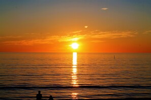 A sunset over a calm sea with a distant buoy.