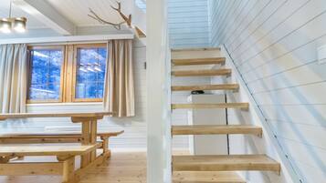 A wooden staircase with a view of snowy trees outside.
