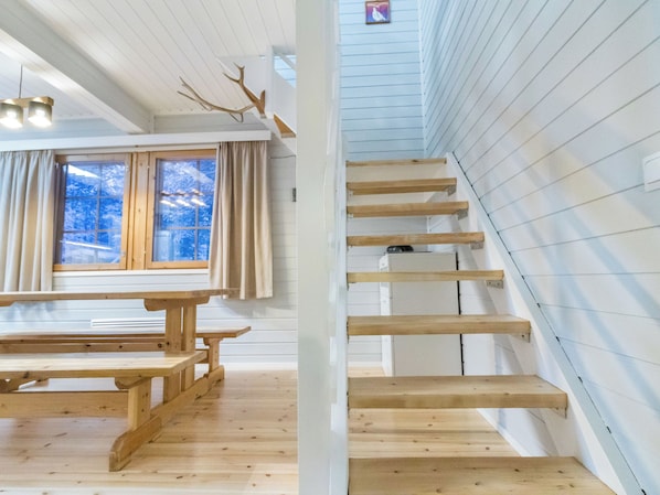 A wooden staircase with a view of snowy trees outside.