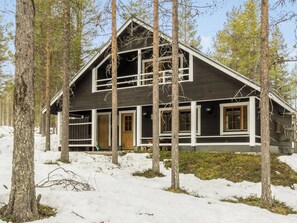 A two-story cabin with a gabled roof, surrounded by trees and snow. - Levilla by Interhome (Kittilä)