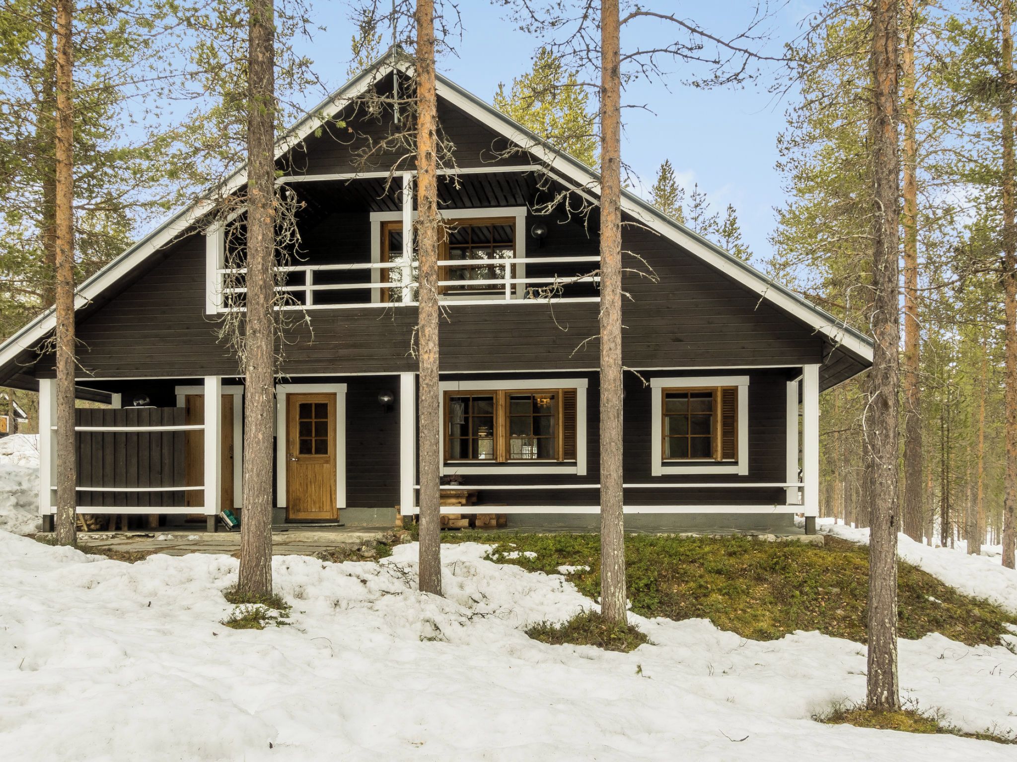 A cabin with a dark wooden exterior, white trim, and a front porch.