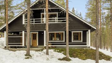 A cabin with a dark wooden exterior, white trim, and a front porch.