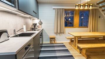 A modern kitchen with a built-in Bosch microwave, a wooden dining table, and a striped rug.