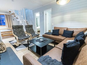 A modern living room with a sofa, two patterned armchairs, a coffee table, and a staircase leading to an upper level. - Levilla by Interhome (Kittilä)