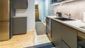 Una cocina moderna con armarios grises, un refrigerador de acero inoxidable, un microondas y un lavamanos.