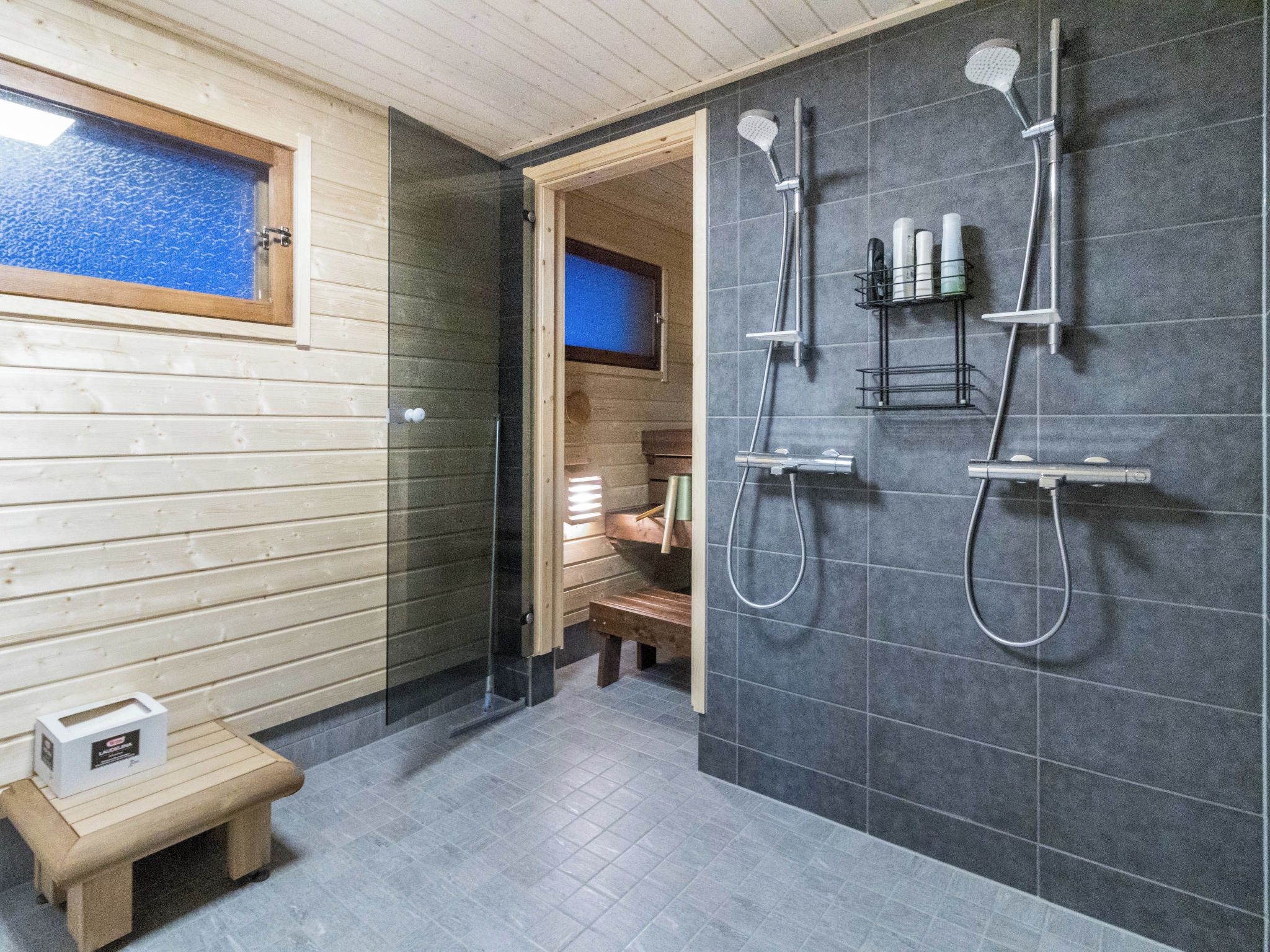 A modern shower area with multiple showerheads and a bench.