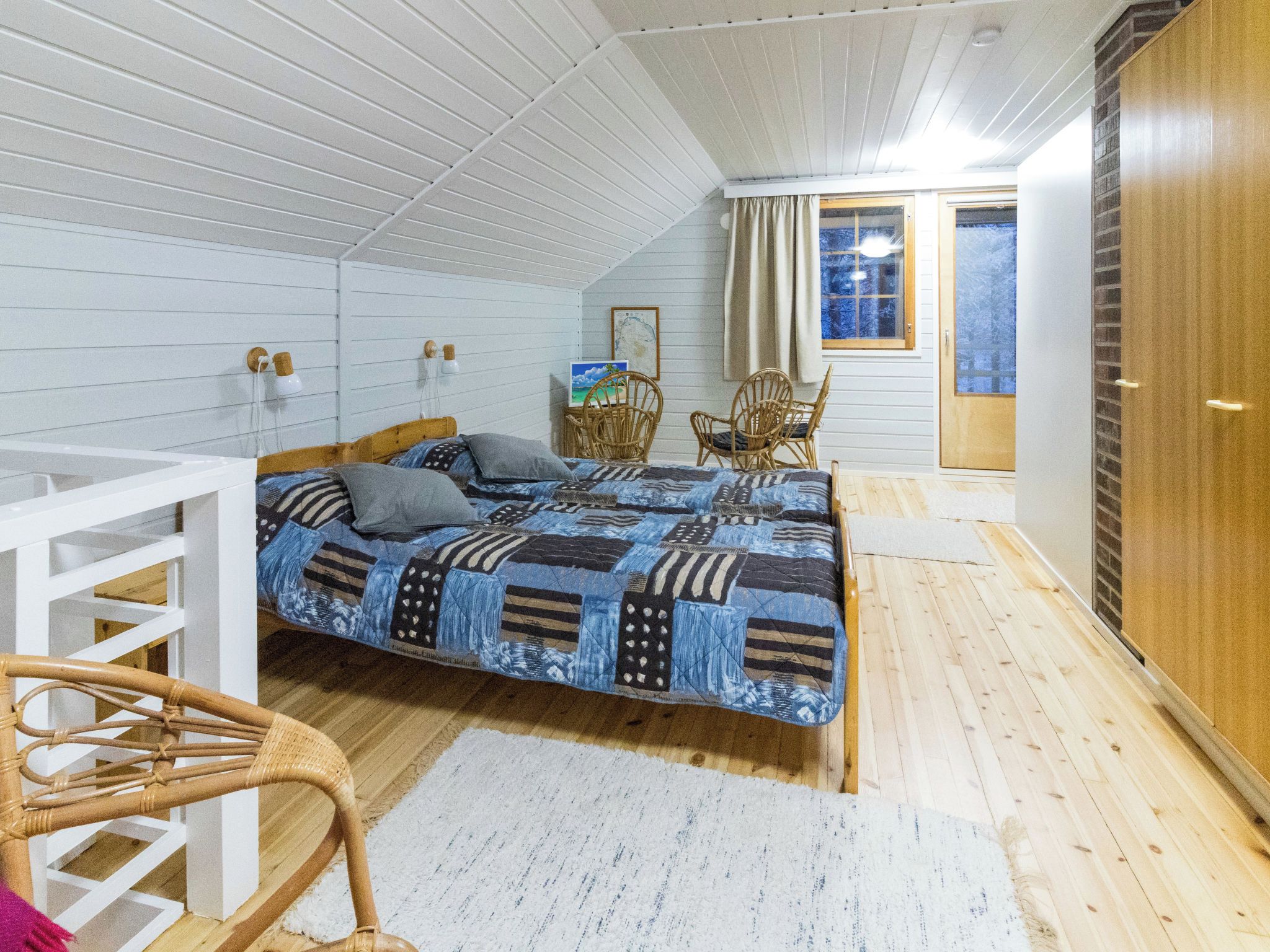 A bedroom with a bed, two chairs, a small table, and a window.