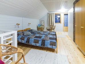A bedroom with a bed, two chairs, a small table, and a window.