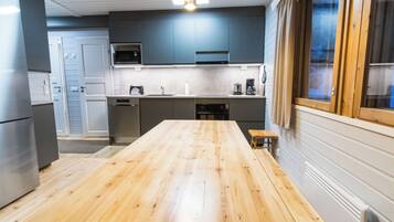 Una cocina moderna con una mesa de madera, electrodomésticos de acero inoxidable y un ventanal con cortinas.