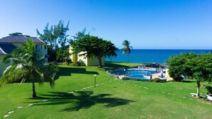 Ein Wohnhaus mit Swimmingpool, gepflegtem Rasen und Meerblick.