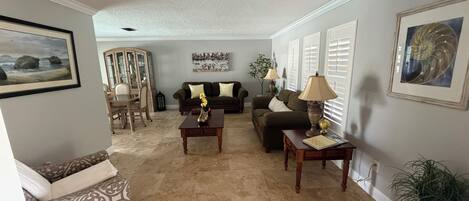A living room with a sofa, two coffee tables, a cabinet, and a potted plant.