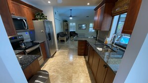 A modern kitchen with stainless steel appliances, wooden cabinets, and a granite countertop. - Dream Vacation Pool Home! On the Water! (Cape Coral)
