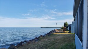 Una propiedad junto al lago con una zona verde, un muelle de madera y un edificio con porche cubierto.
