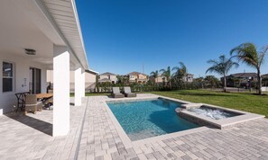 Une piscine avec un jacuzzi, un espace salon extérieur et une vue sur les maisons voisines.
