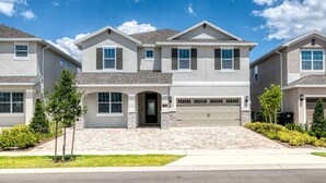 A two-story residential building with a garage, a driveway, and a well-maintained lawn.