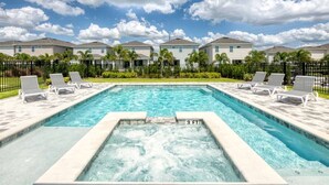 A rectangular swimming pool with a hot tub in the center, surrounded by lounge chairs.