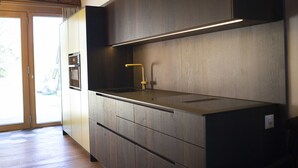 Une cuisine moderne avec des meubles en bois, un four encastré et un plan de travail en acier inoxydable.