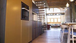 Une cuisine moderne avec des poutres en bois, un four encastré et un coin repas comprenant des chaises et une table en bois.