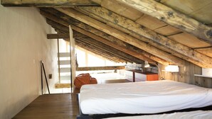 Une pièce avec des poutres en bois, un lit, un bureau et une fenêtre.