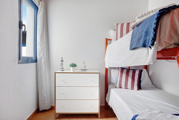 Ein Schlafzimmer mit Etagenbett, Nachttisch und Lampe sowie einem Fenster mit Vorhängen.