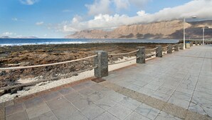 Un paseo marítimo con pavimento de piedra, barandilla de cuerda y faroles.