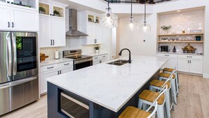 A modern kitchen with a large island, stainless steel appliances, and bar stools. - Expansive Modern Loft House Sleeps 12 (Egg Harbor)