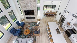 A modern interior with a stone fireplace, seating area, dining space, and kitchen. - Expansive Modern Loft House Sleeps 12 (Egg Harbor)
