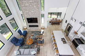A modern interior with a stone fireplace, seating area, dining space, and kitchen.