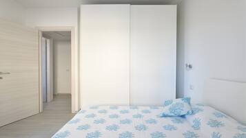 Una camera da letto con un letto, un armadio e una porta che dà su un'altra stanza.