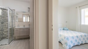 A bedroom with a bed, a nightstand, and a window with curtains.