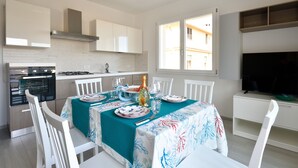 A modern kitchen with white cabinets, a built-in oven, and a dining area with a table set for four.