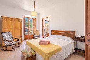 Une chambre à coucher avec un lit, une armoire en bois, un fauteuil à bascule et une vue par la fenêtre.