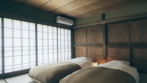 Una habitación tradicional japonesa con suelo de tatami, una puerta corredera y un cabecero de madera.