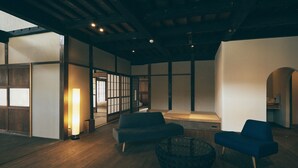 Un interior moderno con suelo de madera, un sofá, una mesa de centro y una puerta corredera tradicional.
