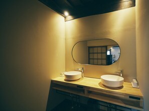 A modern bathroom with two sinks, a large mirror, and a wooden vanity.