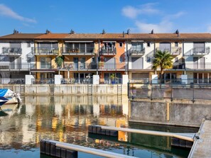 Un immeuble résidentiel situé au bord de l’eau, doté de balcons, d’un quai et donnant sur une étendue d’eau calme.