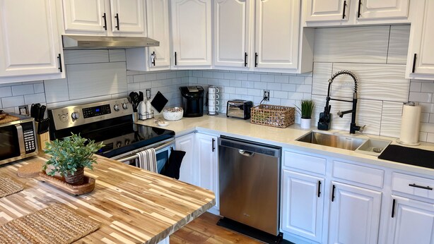 A modern kitchen with white cabinetry, stainless steel appliances, and a wooden countertop. - Sellwood Custom Private Space (Portland)
