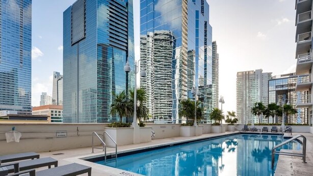 A rooftop pool with lounge chairs and palm trees, surrounded by high-rise buildings. - Mesmerizing Studio Brickell +Free Parking + Gym+Pool (Miami)