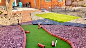 A miniature golf course with a green putting area, red brick borders, and a small flagstick.