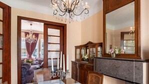A dining area with a wooden table, chairs, a chandelier, and a cabinet with glass doors. - Jasmine by Interhome (Mol)