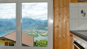 Eine Küche mit Holzwand, einer Uhr und einem Fenster mit Blick auf ein Tal und Berge.