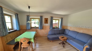 Ett mysigt rum med en träbänk, ett matbord, en blå soffa och ett litet bord med en lampa.