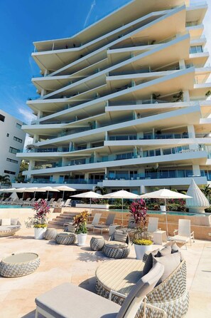 A multi-story hotel with outdoor seating and a pool area.