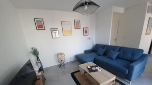 A living room with a blue sofa, a wooden coffee table, and a TV on a stand.